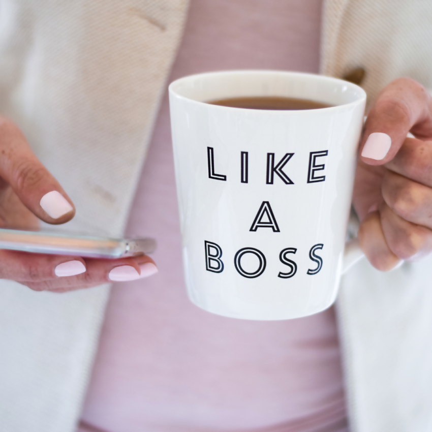 A lady holding a mug and a mobile phone. the mug has the slogan like a boss on it